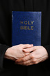 Priest holding holy bible, close up
