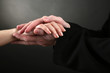 Priest holding woman hand, on black background
