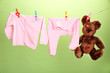 Baby clothes hanging on clothesline, on color background