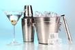 Metal ice bucket and shaker and cocktail on blue background