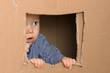 staunendes Baby schaut vorsichtig aus Fenster