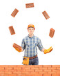 Construction worker juggling with bricks behind a brick wall