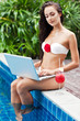 Young woman relaxing near the pool with laptop