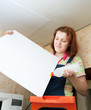  woman glues ceiling tile at home