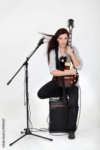 Photo: Musician hugging her guitar and posing with her equipment Musician hugging her guitar and posing with her equipment