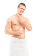 Handsome young man in towel applying skin cosmetics