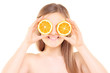 Young pretty female holding an orange half in front of her eyes