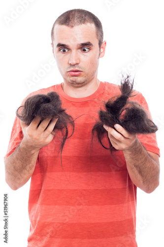 Photo: Shocked bald man holding his shaved hair Shocked bald man holding his shaved hair