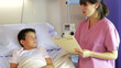 Female Doctor Talking To Boy In Hospital Bed