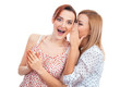 Two happy young girl friends talking or whispering