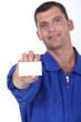 Man in blue overalls holding a business card left blank