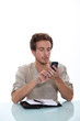 Photo: Man texting on his cellphone with an open diary on a white desk Man texting on his cellphone with an open diary on a white desk