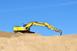 new yellow excavator working on sand dunes