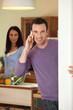 Photo: Man making a call whilst wife prepares meal Man making a call whilst wife prepares meal