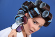 Woman with her hair in rollers holding a pair of sunglasses