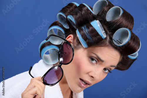 Photo: Woman with her hair in rollers holding a pair of sunglasses Woman with her hair in rollers holding a pair of sunglasses
