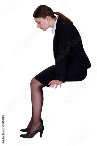Photo: businesswoman sitting in profile with legs dangling businesswoman sitting in profile with legs dangling