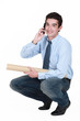 Squatting young professional talking on his mobile phone