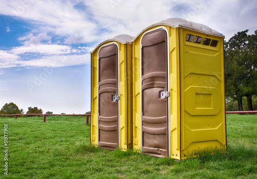 Photo: Two yellow portable toilets at a park Two yellow portable toilets at a park