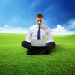 Foto: business man with notebook sitting on grass business man with notebook sitting on grass
