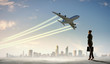 Business woman looking at airplane in sky