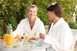 Photo: Two young women having breakfast in the garden Two young women having breakfast in the garden