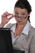 Serious businesswoman watching over her glasses