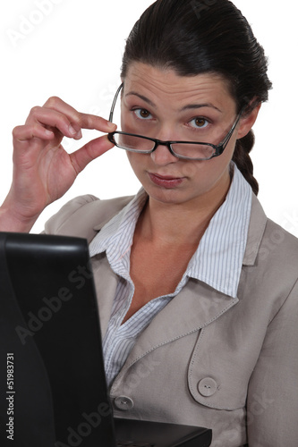 Photo: Serious businesswoman watching over her glasses Serious businesswoman watching over her glasses