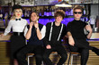 Four popular rock band in black and white pose near bar counter.