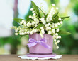 Beautiful lily of the valley in vase on nature background