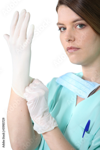 Photo: Female medic in scrubs pulling on a rubber glove Female medic in scrubs pulling on a rubber glove