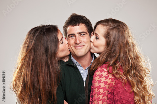 Photo: two young women kissing handsome man standing between them two young women kissing handsome man standing between them