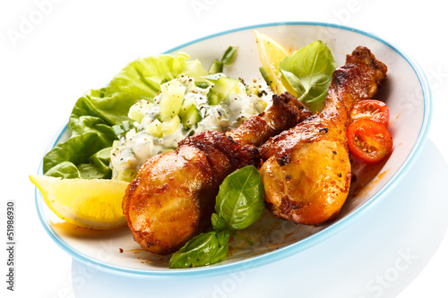 Photo: Grilled chicken legs and vegetables on white background Grilled chicken legs and vegetables on white background