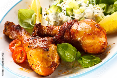 Photo: Grilled chicken legs and vegetables on white background Grilled chicken legs and vegetables on white background