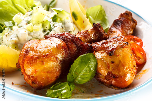 Photo: Grilled chicken legs and vegetables on white background Grilled chicken legs and vegetables on white background