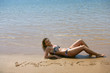 Seductive blond laying on the beach in bikini