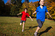 Girl and boy running, jumping in park - focus on boy