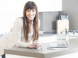 beautiful young female using a laptop at home taking a coffee