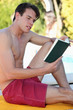 Photo: Man sat by pool reading book Man sat by pool reading book