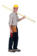 Photo: young carpenter in studio carrying plank over his shoulder young carpenter in studio carrying plank over his shoulder