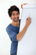 Photo: young man writing with marker on a white board young man writing with marker on a white board
