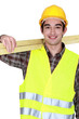 Foto: portrait of young joiner carrying planks over shoulder portrait of young joiner carrying planks over shoulder