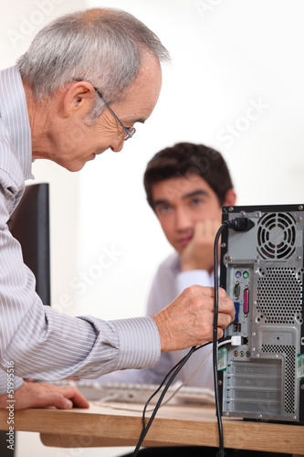 Photo: Man plugging a cable into the back of a hard drive Man plugging a cable into the back of a hard drive