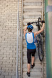Professional cyclist coming up the steps with bicycle