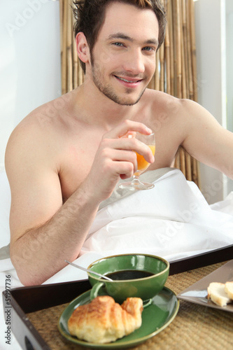 Photo: Man having breakfast in bed Man having breakfast in bed
