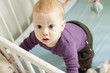 Top view of adorable baby boy trying to stand up in his cot