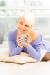 Pretty woman with mug on the floor laying on a pillow