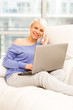 Foto: Smiling woman on the sofa with computer and phoning Smiling woman on the sofa with computer and phoning