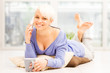 Foto: Smiling woman with mug on the floor while phoning Smiling woman with mug on the floor while phoning