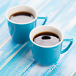 Photo: Two turquoise espresso cups on wooden boards, close-up Two turquoise espresso cups on wooden boards, close-up